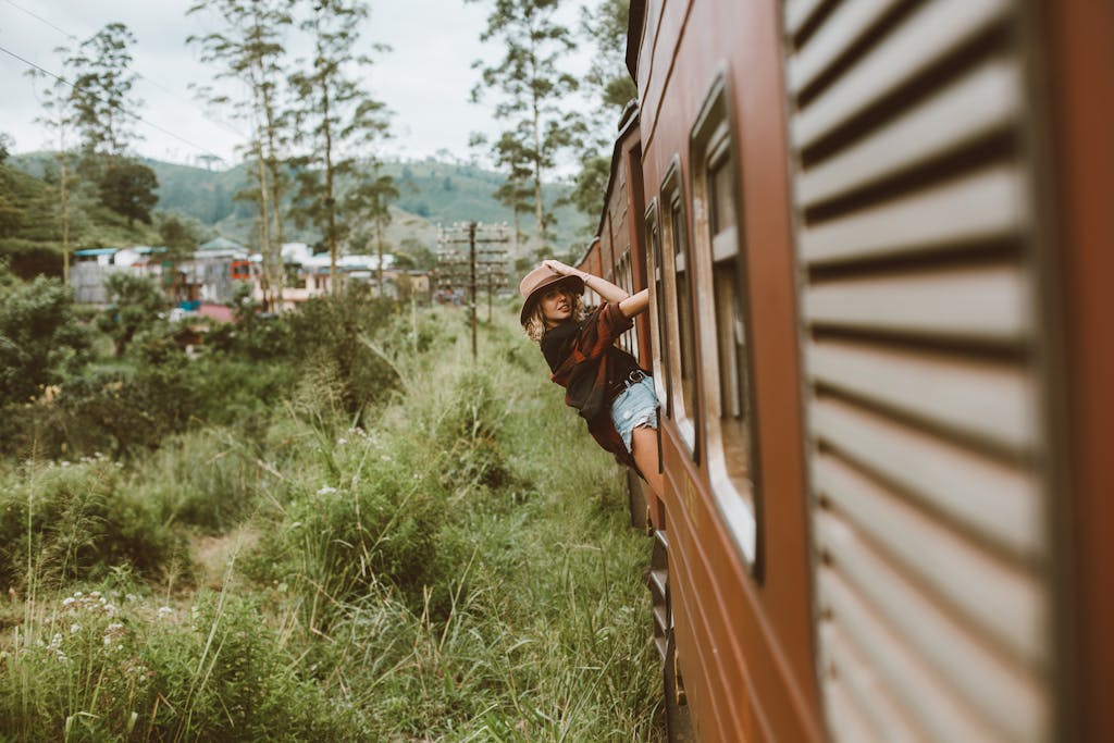 Image Gallery 2 A young woman in casual attire enjoys a scenic train ride through lush countryside.